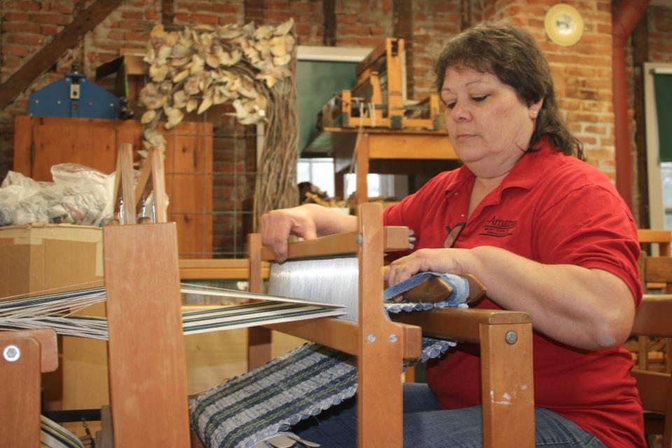 Linda Grabau sits in front of a loom inside the Amana Art Guild Center and weaves a rug made out of denim, May 5.