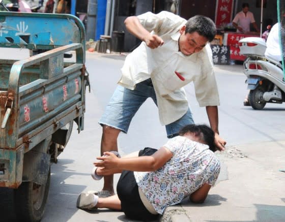 A man from Anhui, China, was seen beating up his wife in public because she would not listen to him. (Image: chinaSMACK.com)