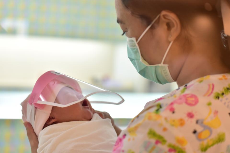 A nurse holding a newborn baby wearing a face shield &mdash; perhaps not happily &mdash; at Praram 9 Hospital. (Photo: LILLIAN SUWANRUMPHA via Getty Images)