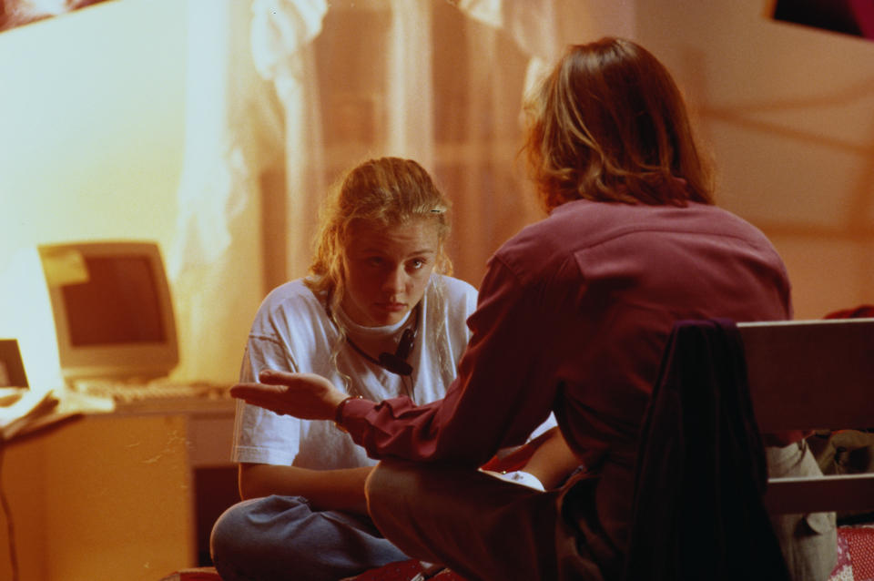 A parent and child sit facing each other in a candid conversation, expressing concern and support