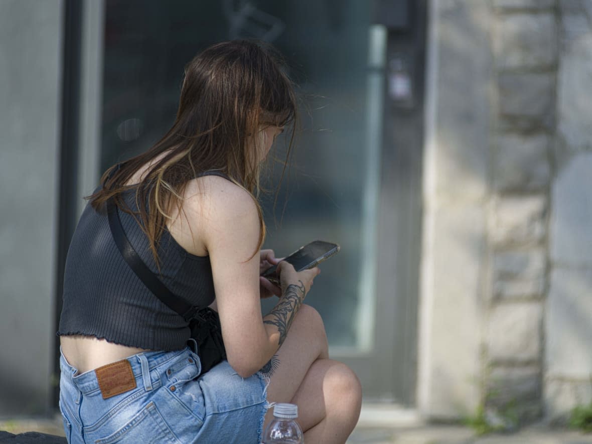 A person uses a cellphone in Montreal in July 2023. Today, two new reports from Women's Shelters Canada reveal the prevalence of technology-facilitated gender-based violence. (CBC/Radio-Canada - image credit)