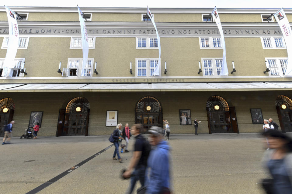 FILE - In this Aug. 14, 2019, file photo, people walk by the opera house in Salzburg, Austria, where singer Placido Domingo is scheduled to perform 'Luisa Miller' by Giuseppe Verdi. Domingo is scheduled to appear onstage at the Salzburg Festival Aug. 25, 2019, to perform for the first time since multiple women have accused the opera legend of sexual harassment in allegations brought to light by The Associated Press. (AP Photo/Kerstin Joensson, File)