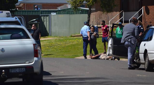 A second Facebook image revealed the red shirted man was likely not in the police officer's sights when the pistol was fired. He is seen again as another man lays handcuffed on the ground. Photo: Facebook