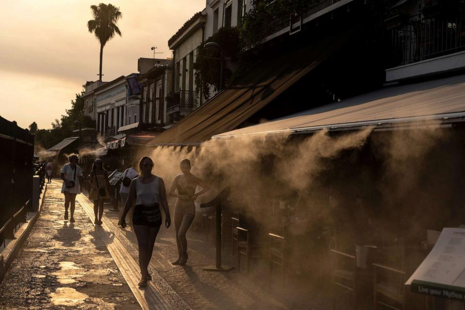 PHOTO: People walk next a mist machine to cool down, in Monastiraki district of Athens, July 20, 2023. (Petros Giannakouris/AP)