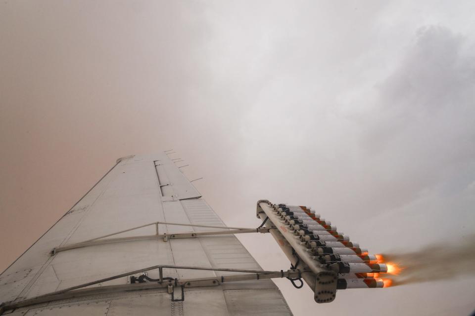 plane wing with array of tubes attached to the back flaring out gas in a thick cloud