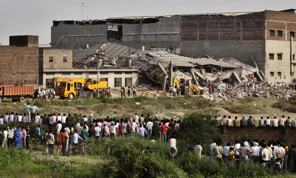 Workers and residents watch rescue operations at the site of a collapsed factory in Jalandhar, India, Monday, April 16, 2012. Several people are feared to be trapped after a three-story building of a factory collapsed after a blast in the factory's boiler, according to local reports. (AP Photo/Altaf Qadri)