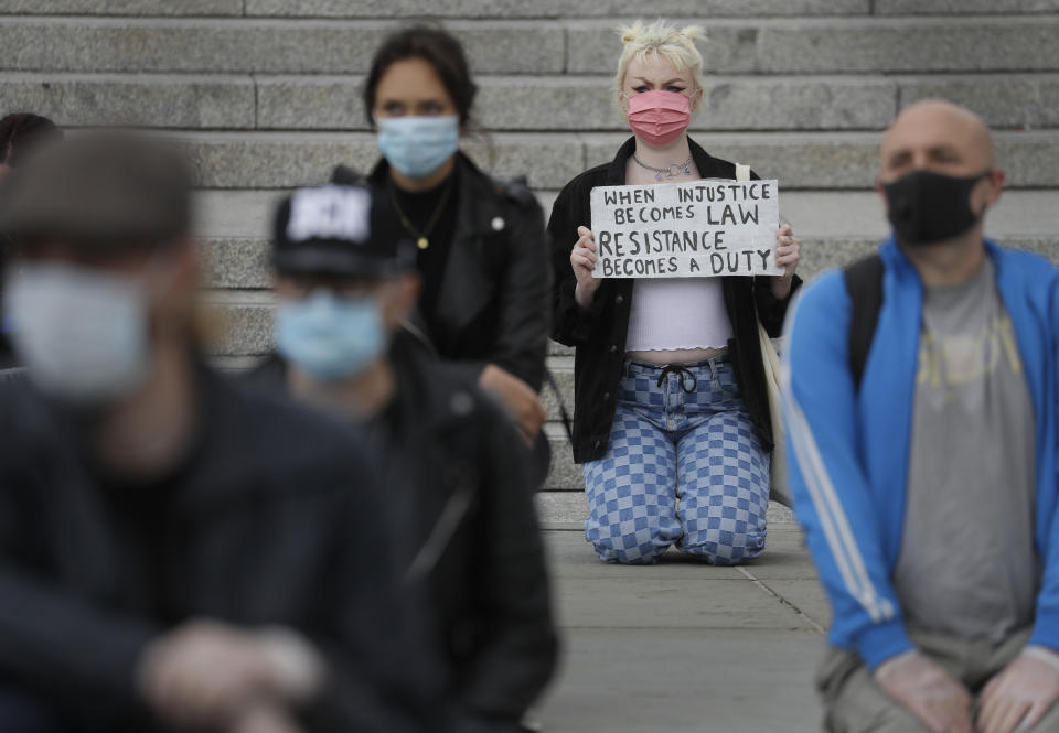 Demonstrators kneel in Trafalgar Square in London, Friday, June 5, 2020, to protest against the recent killing of George Floyd by police officers in Minneapolis, USA, that has led to protests in many countries and across the US. A US police officer has been charged with the death of George Floyd. (AP Photo/Kirsty Wigglesworth)