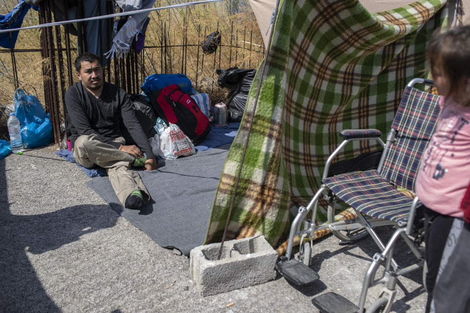 Homeless Afghan refugee Ayoub Husseini, who has lost the use of his legs after a construction accident, sits on a blanket with his belongings on the terrace of a commercial building on the island of Lesbos. Greece, Monday, Sept. 14, 2020. Ayoub who hopes to receive medical treatment for his injuries in Europe, is one of thousands of asylum-seekers left homeless after a fire gutted Moria refugee camp on the island. (AP Photo/Petros Giannakouris)