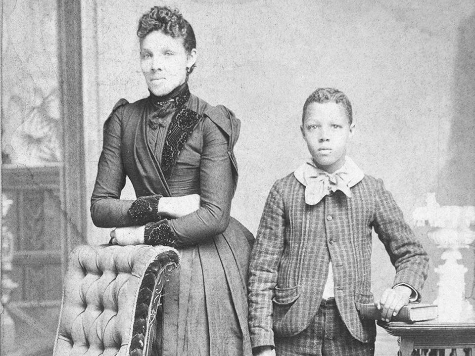 Unidentified standing figures: woman, her folded arms leaning on back of chair, and young man, probably her son, left hand on book, c1890. Additional title: Domestic life. Creator: J. N. Wilson.