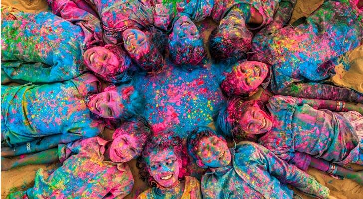 Gypsy Indian children playing happy holi on sand dunes in desert village, Thar Desert, Rajasthan, India.