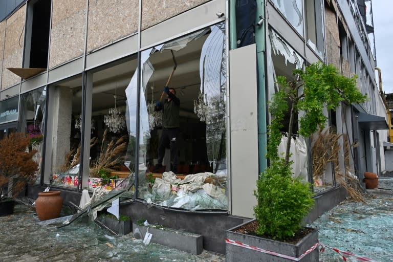 Un hombre retira fragmentos de cristal de la ventana rota de una cafetería tras un ataque con misiles en Járkov el 24 de abril de 2024 (SERGEY BOBOK)