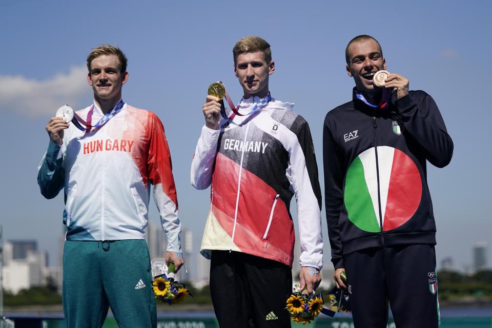 Silver medalist Kristof Rasovszky, from left, of Hungary, gold medalist Florian Wellbrock, of Germany, and bronze medalist Gregorio Paltrinieri, of Italy, pose for photos during a victory ceremony for the men's marathon swimming event at the 2020 Summer Olympics, Thursday, Aug. 5, 2021, in Tokyo, Japan. (AP Photo/Jae C. Hong)