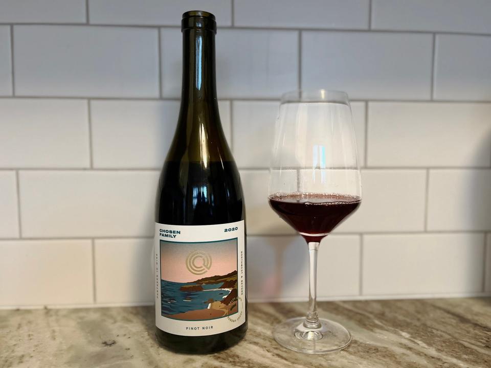 A bottle of Chosen Family pinot noir sits next to a small glass on a counter.