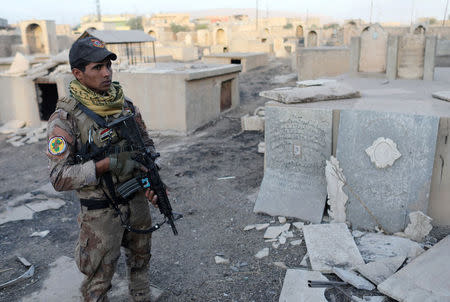 An Iraqi special forces soldier stands in a Christian cemetery inside a church compound damaged by Islamic States fighters in Bartella, east of Mosul, Iraq October 21, 2016. REUTERS/Goran Tomasevic