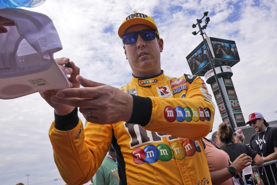 Kyle Busch gives an autograph during driver introductions prior to a NASCAR Cup Series auto race at Richmond Raceway, Sunday, Aug. 14, 2022, in Richmond, Va. (AP Photo/Steve Helber)
