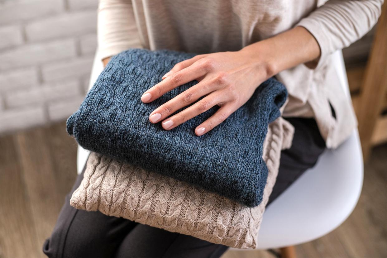 Woman's hands holding knitted clothes