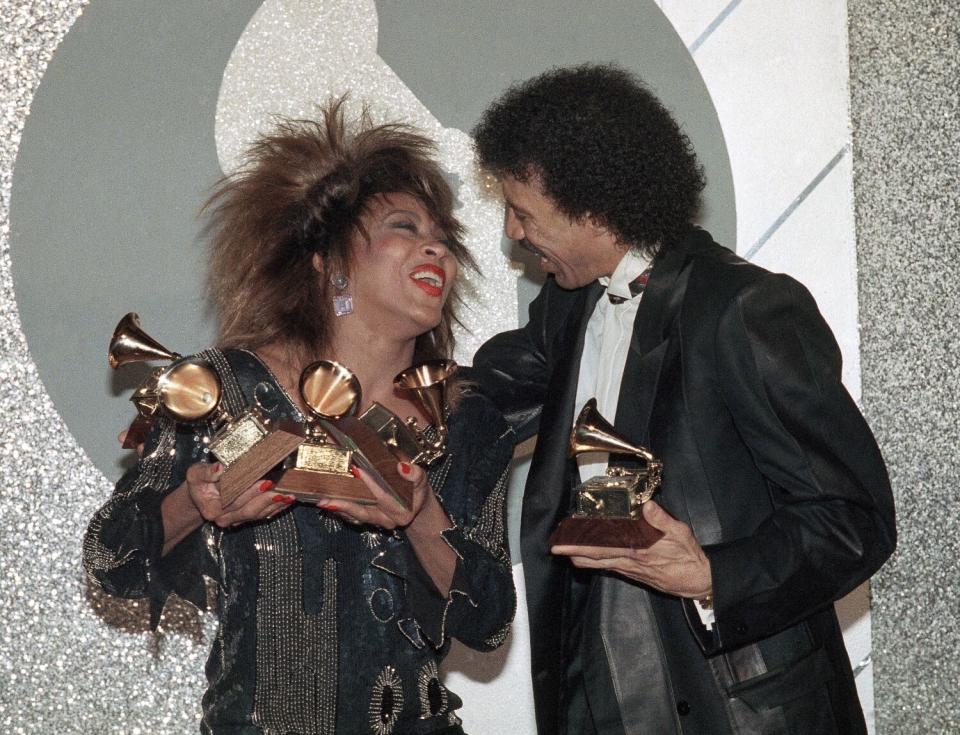 Tina Turner with Lionel Richie holding multiple grammys, smiling at each other