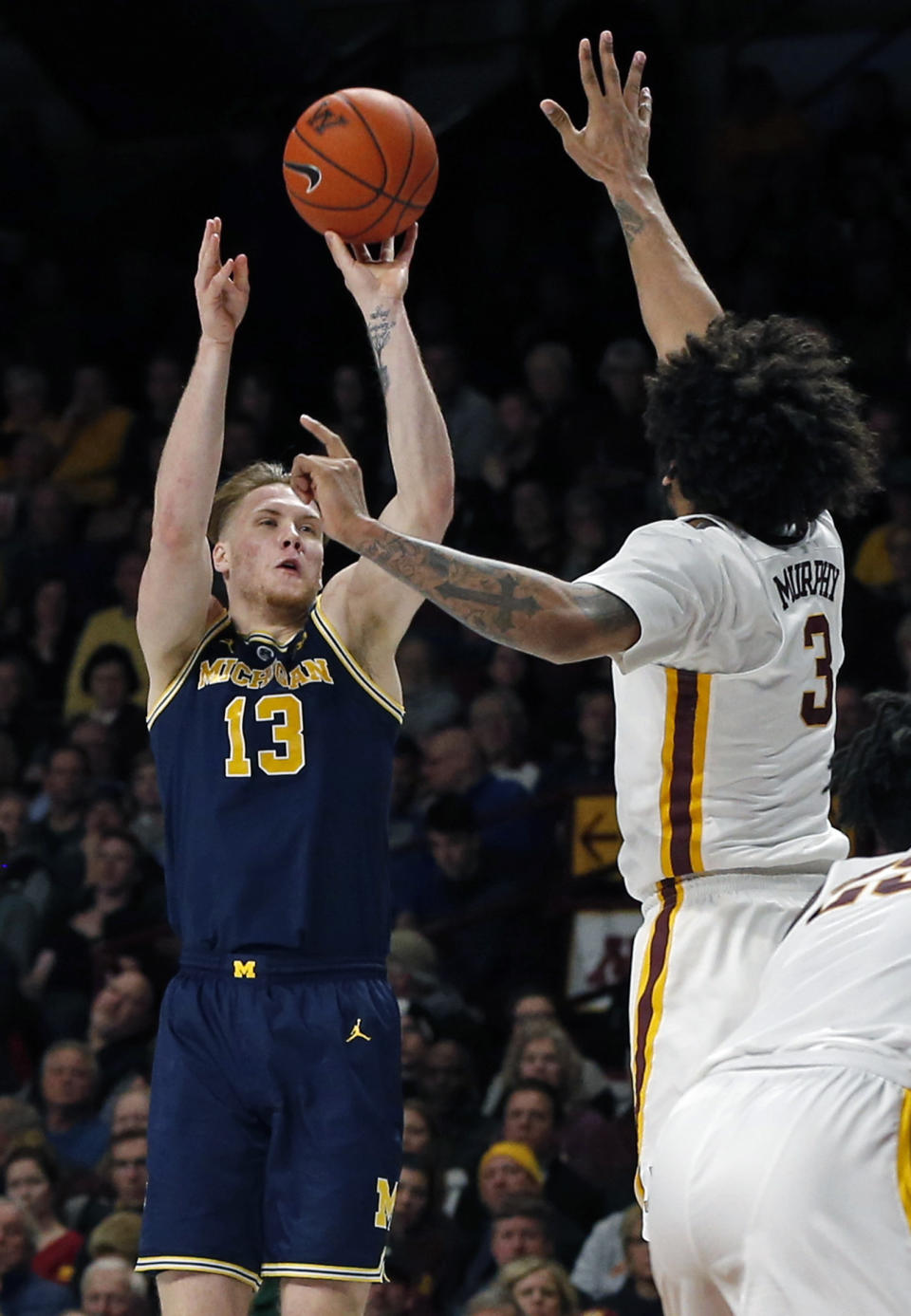 Michigan's Ignas Brazdeikis, left, shoots over Minnesota's Jordan Murphy in the second half of an NCAA college basketball game Thursday, Feb. 21, 2019, in Minneapolis. (AP Photo/Jim Mone)