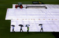 Cricket - Australia v South Africa - Second Test cricket match - Bellerive Oval, Hobart, Australia - 13/11/16 A security guard accompanies umpires Richard Kettleborough, Aleem Dar and Mick Martell as they hold umbrellas while inspecting the covered pitch as rain falls during the second day of the second test between Australia and South Africa. REUTERS/David Gray