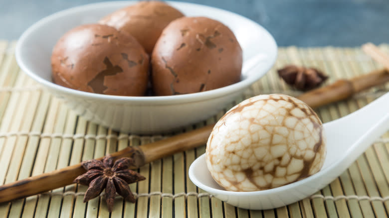 Tea eggs in white dish next to white spoon