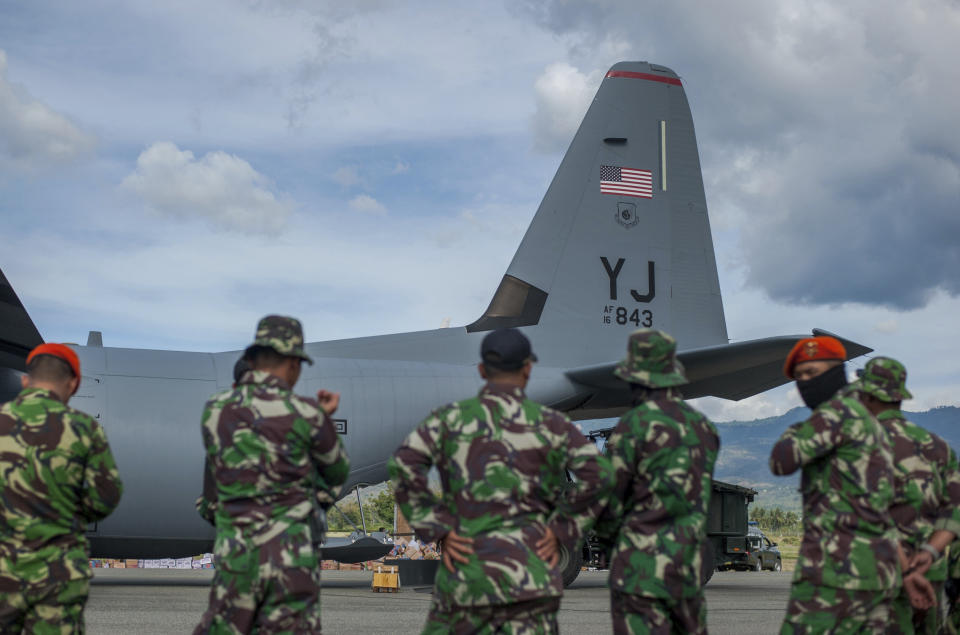 Indonesian soldiers stand near a U.S. Air Force cargo plane delivering relief goods at Mutiara Sis Al-Jufrie Airport in Palu, Central Sulawesi, Indonesia, Sunday, Oct. 7, 2018. Indonesia's disaster agency said the number of dead had climbed and many more people could be buried, especially in the Palu neighborhoods of Petobo and Balaroa, where thousands of homes were damaged or sucked into deep mud when the Sept. 28 quake caused loose soil to liquefy. (AP Photo/Fauzy Chaniago)
