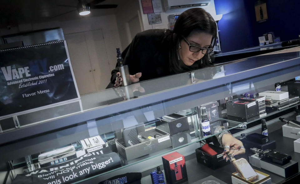 In this Tuesday, Oct. 8, 2019, photo Spike Babaian, owner of several Vape New York stores, works in her East Harlem store in New York. Sales at small businesses that sell vaping products have plunged since August, when reports of vaping-related illnesses and deaths began. “We can never undo the government going on the news and saying it’s not safe to vape. The damage has been done,” says Babaian, who has been in business for eight years. (AP Photo/Bebeto Matthews)