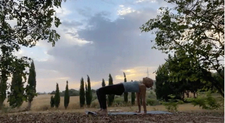 Woman practicing yoga outside at sunrise in reverse tabletop