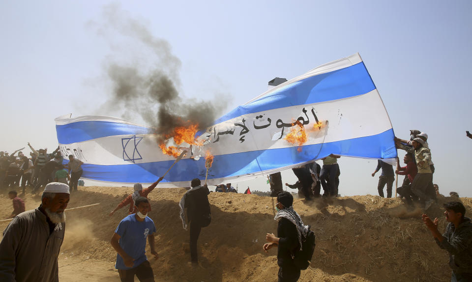 <p>Palestinian protesters burn a representation of an Israeli flag during clashes with Israeli troops along Gaza’s border with Israel, Friday, April 6, 2018. Arabic writing says, ” Death to Israel.” (Photo: Adel Hana/AP) </p>