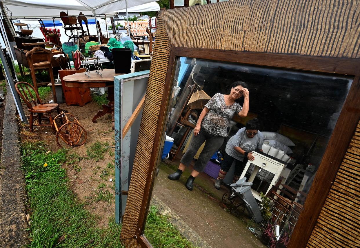 Sisters Juanita Aumala, left, and Luz Punto, both of Tampa, Florida, move items out from their tent after the heavy rain stopped Monday during set up day at Brimfield Flea Market. They were helping to setup Vintage Woodhouse.