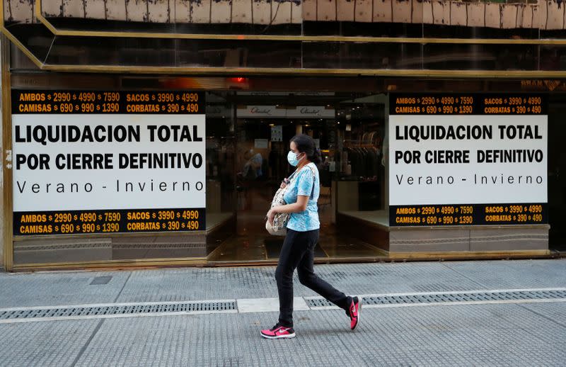 Una peatona pasa por delante de un comercio con una pancarta en la que se lee "Liquidación total por cierre definitivo", cerca del Obelisco de Buenos Aires, Argentina.