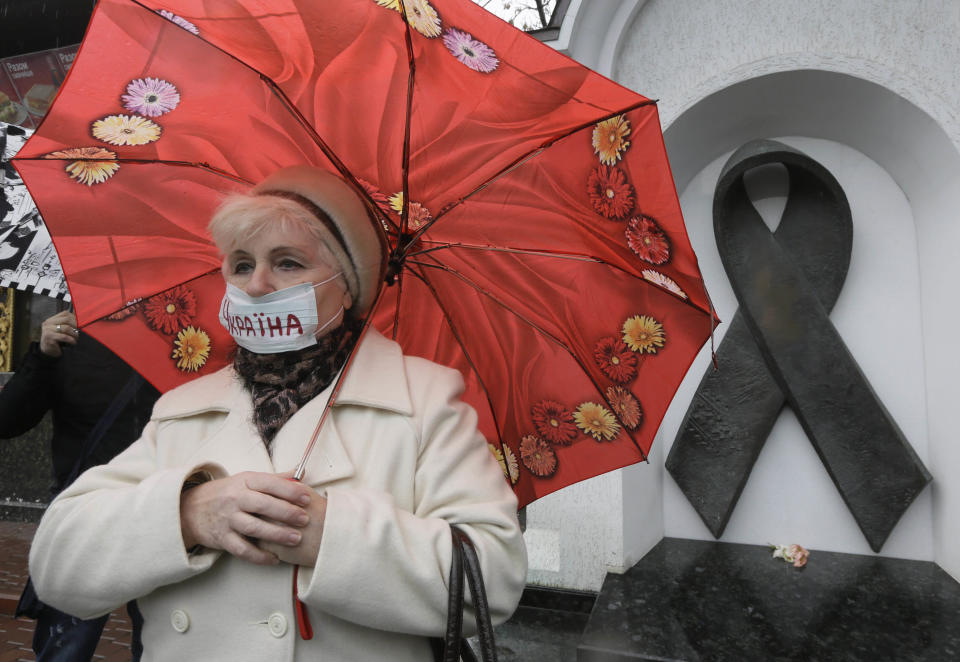 FILE - In this Tuesday, Nov. 13, 2012 file photo, a Ukrainian woman wearing a medical mask demonstrates in front of the memorial monument to AIDS victims in Kiev, Ukraine. An estimated 230,000 Ukrainians, or about 0.8 percent of people aged 15 to 49 in a population of 46 million, are living with HIV, the virus that causes AIDS. Some 120,000 are in urgent need of anti-retroviral therapy, which can greatly prolong and improve the quality of their lives. But due to a lack of funds, less than a quarter are receiving the drugs, one of the lowest levels in the world. (AP Photo/Efrem Lukatsky)