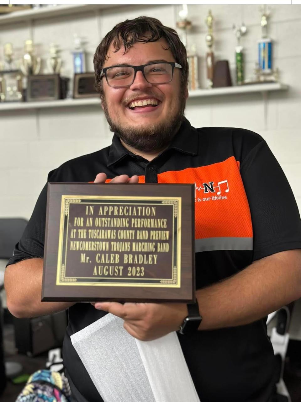 Newcomerstown High band director Caleb Bradley shows off the award the band recently received at the Tuscarawas County Band Preview.