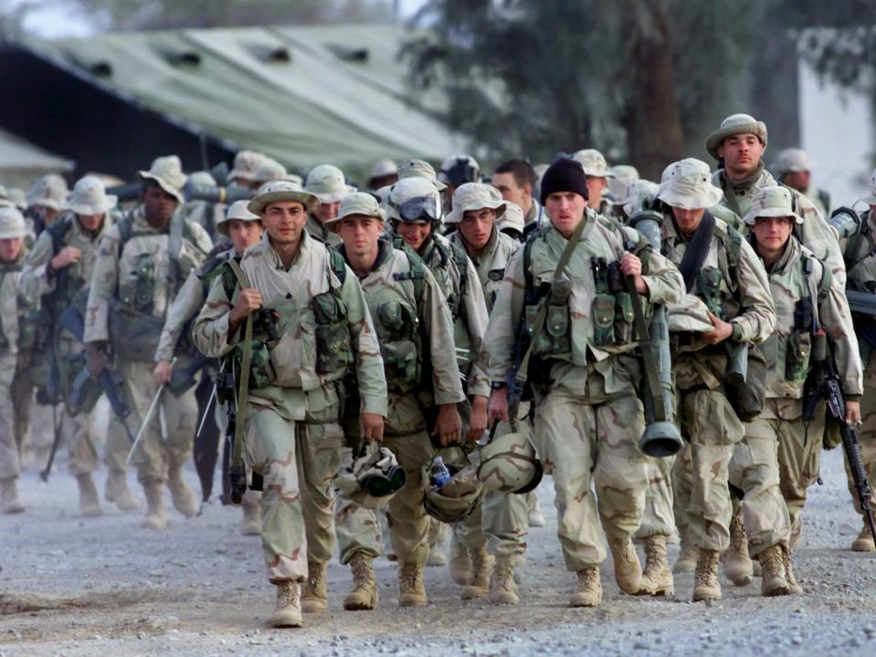 A group of US Marines walk with full battle gear.