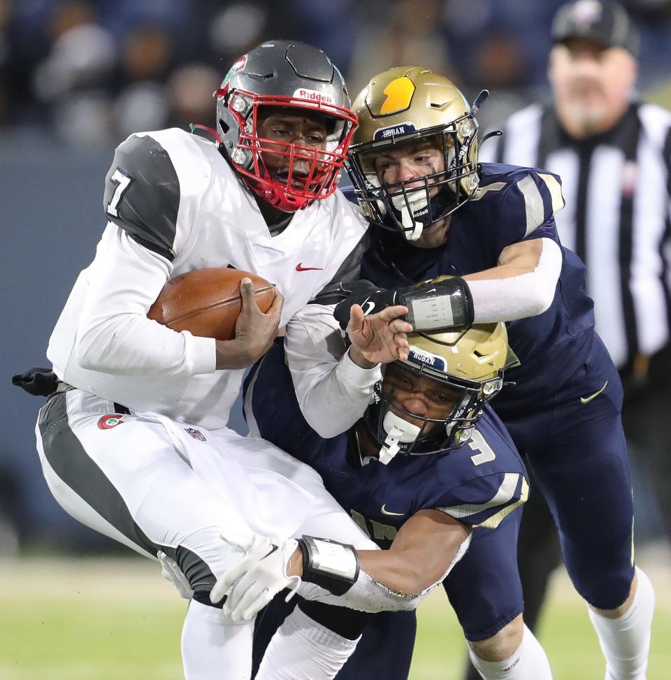 Hoban linebacker Rickey Williams, bottom, and Tanner Mintz bring down Toledo quarterback Ty'Wuan Clark during the first half of the OHSAA Division II State Championship football game at Tom Benson Hall of Fame Stadium, Thursday, Dec. 1, 2022, in Canton, Ohio.