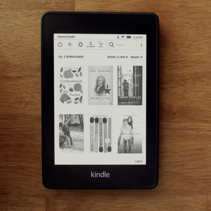 A Kindle Paperwhite turned on to show the layout out six books on the menu screen 