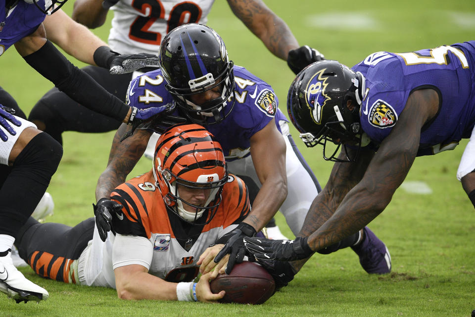 Cincinnati Bengals quarterback Joe Burrow, bottom left, tries to retrieve his fumble as Baltimore Ravens cornerback Marcus Peters (24) and defensive end Jihad Ward (53) challenge him for the recovery during the second half of an NFL football game, Sunday, Oct. 11, 2020, in Baltimore. The ball bounced out of bounds and the Bengals retained possession. (AP Photo/Nick Wass)