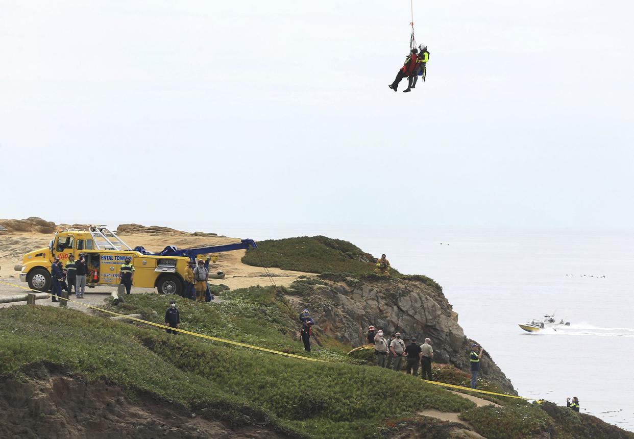 A long line from Sonoma County Sheriff's helicopter Henry 1 is used to safely transport rescue personnel to a beach below after a vehicle plummeted from the Bodega Head parking lot in Bodega Bay, Calif., landing upside down 100 feet below, killing two people in the SUV, Saturday, April 3. 