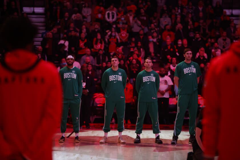 Boston forward Matt Ryan, second from left, stands for the national anthem before an NBA last March.