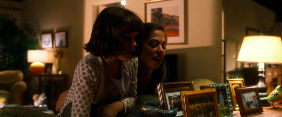 Babysitter Jessica and the daughter near family photos, one of which has Emma Stone's character in it
