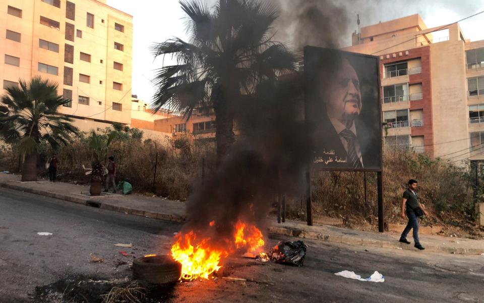 A man walks near a burning fire blocking a road during a protest against mounting economic hardships in Beirut last mont - Issam Abdallah/Reuters