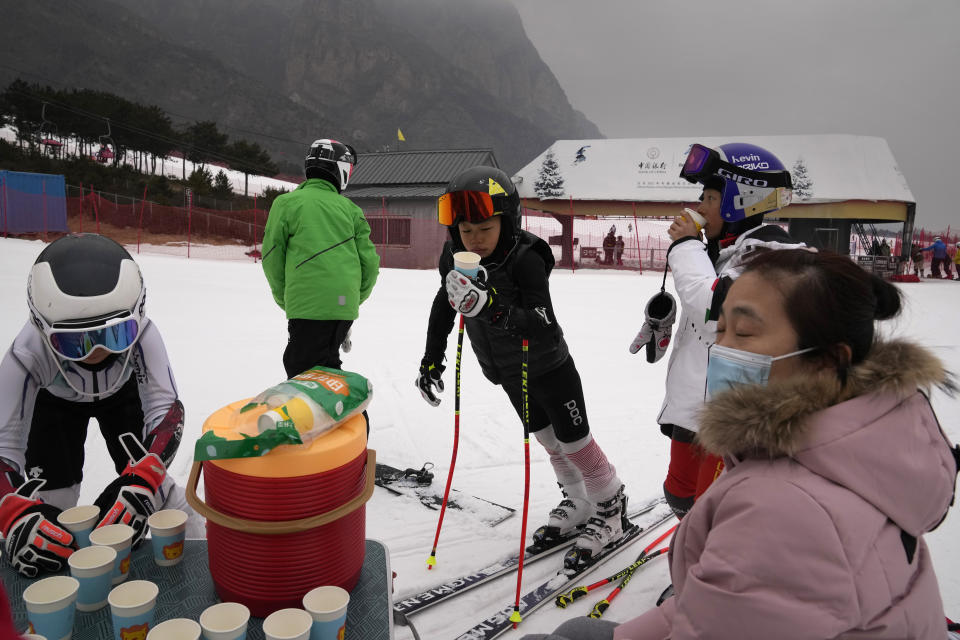Young skiers stop for a water break on the slope of the Vanke Shijinglong Ski Resort in Yanqing on the outskirts of Beijing, China, Thursday, Dec. 23, 2021. The Beijing Winter Olympics is tapping into and encouraging growing interest among Chinese in skiing, skating, hockey and other previously unfamiliar winter sports. It's also creating new business opportunities (AP Photo/Ng Han Guan)