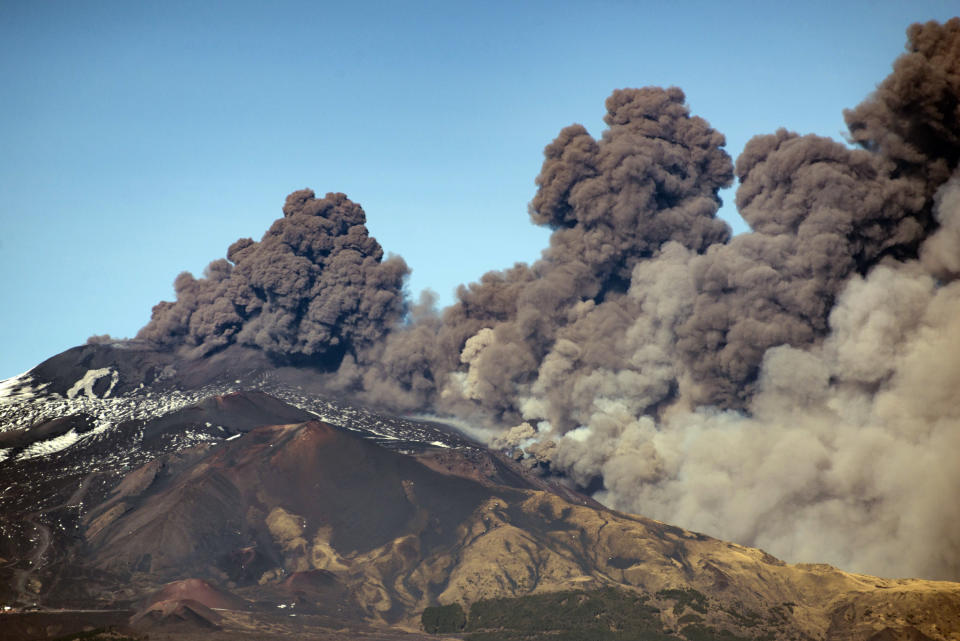A smoke column comes out of the Etna volcano in Catania, Italy, Monday, Dec. 24, 2018. The Mount Etna observatory says lava and ash are spewing from a new fracture on the active Sicilian volcano amid an unusually high level of seismic activity. (AP Photo/Salvatore Allegra)