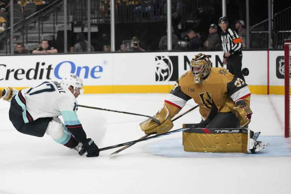 Seattle Kraken center Jaden Schwartz (17) attempts to knock the puck past Vegas Golden Knights goaltender Adin Hill (33) during the first period of an NHL hockey game Tuesday, Oct. 10, 2023, in Las Vegas. (AP Photo/John Locher)