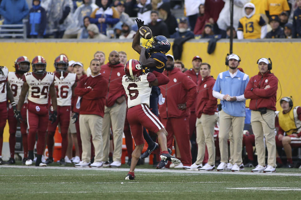 West Virginia wide receiver Sam James (13) catches a pass while defended by Oklahoma defensive back Trey Morrison (6) during the second half of an NCAA college football game in Morgantown, W.Va., Saturday, Nov. 12, 2022. (AP Photo/Kathleen Batten)