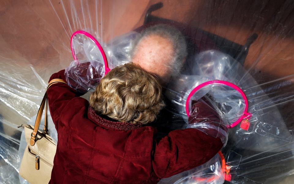 Diane Rossi embraces her husband, Arthur Rossi, through a hug tent at the Crossroads Senior Living community - Michael Ciaglo/ Getty Images North America