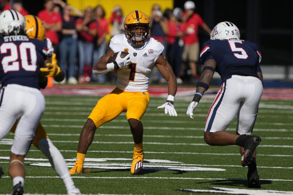 Arizona State running back Xazavian Valladay (1) runs the ball in front of Arizona safety Christian Young (5) in the first half of an NCAA college football game, Friday, Nov. 25, 2022, in Tucson, Ariz. (AP Photo/Rick Scuteri)