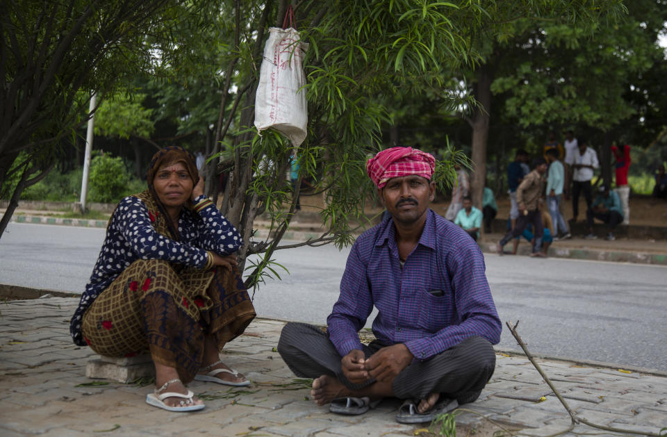 A couple look on as they wait at labor chowk - a bazaar at the junction of four roads where hundreds of workers gather daily at daybreak to plead for work in Manesar Industrial Area, Haryana state, India, Aug. 4, 2022. Scenes like this are an everyday reality for millions of Indians, the most visible signs of economic distress in a country where raging unemployment is worsening insecurity and inequality between the rich and poor. (AP Photo/Bhumika Saraswati)