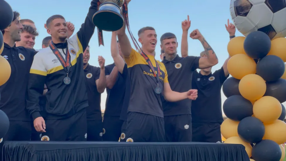 Boston United players lift the trophy