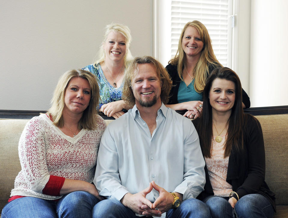 FILE - In this July 10, 2013, file photo, Kody Brown of "Sister Wives," a popular TV reality series about a polygamous family, poses with his wives, at one of their previous homes in Las Vegas. The recent slaying in Mexico of nine people who belonged to a Mormon offshoot community where some people practice polygamy shines a new spotlight on the ongoing struggle for the mainstream church to fight the association with plural marriage groups because of its past. ( Jerry Henkel/Las Vegas Review-Journal via AP, File)