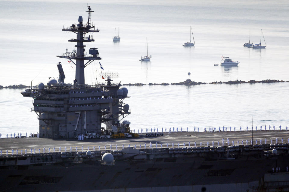 Sailors man the rails as the USS Theodore Roosevelt aircraft carrier makes its way into San Diego Bay Thursday, July 9, 2020, seen from San Diego. The carrier returned home to San Diego Thursday, led by a new captain who came aboard after the previous commander was fired and the Navy secretary resigned over the handling of a massive COVID-19 outbreak on board. (AP Photo/Gregory Bull)